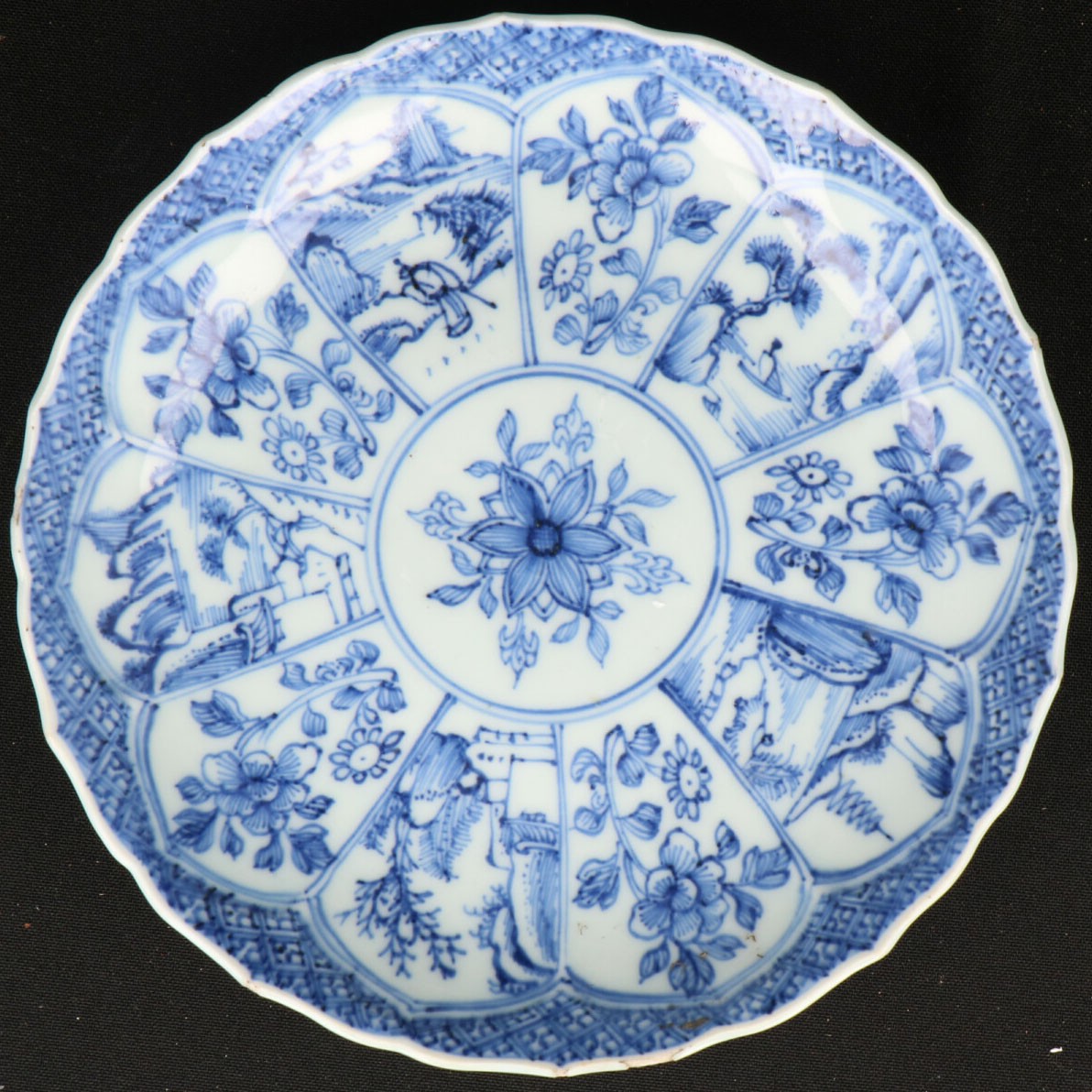 Een Porseleinen bord met lotusblad decor waarin rivierlandschap en floraal decor. China, Qianglong.
