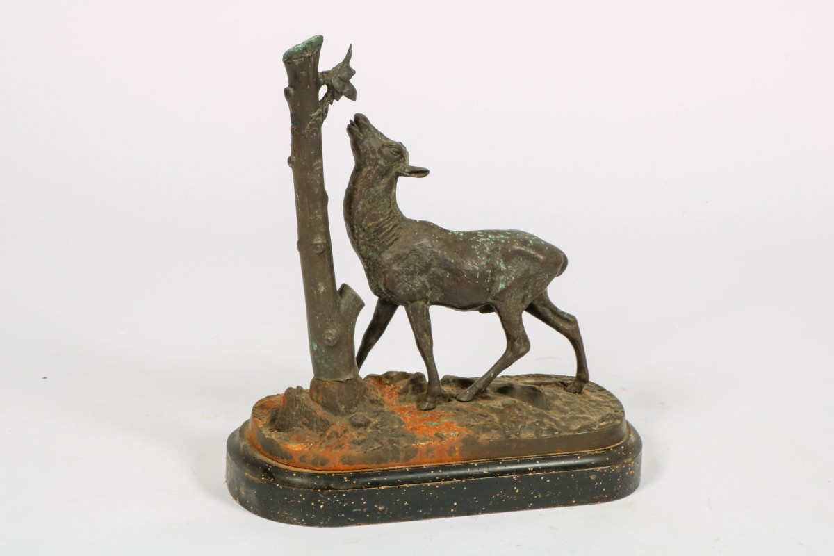 Een bronzen sculptuur van een ree bij een boom, ca. 1900.