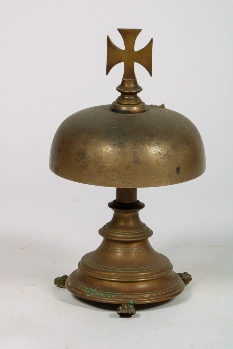 Een bronzen altaarbel op voet, bekroond met een crucifix, ca. 1920.