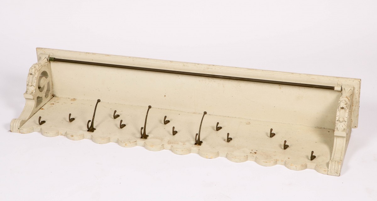 Een wit geschilderde kapstok met hoedenplank.